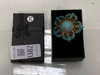 Lot 1382  
            Marchington SR13 - Parcel Delivery Only 

                
A VINTAGE GOLD COLOURED FILIGREE BROOCH SET WITH POLISHED BLUE STONES, BOXED: LOC...
