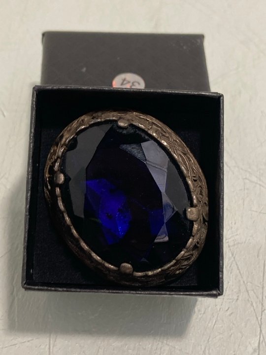 Lot 872  
            Marchington SR13 - Parcel Delivery Only 

                
AN ANTIQUE BROOCH FEATURING A LARGE FACET CUT BLUE STONE IN A SILVER COLOURED SET...